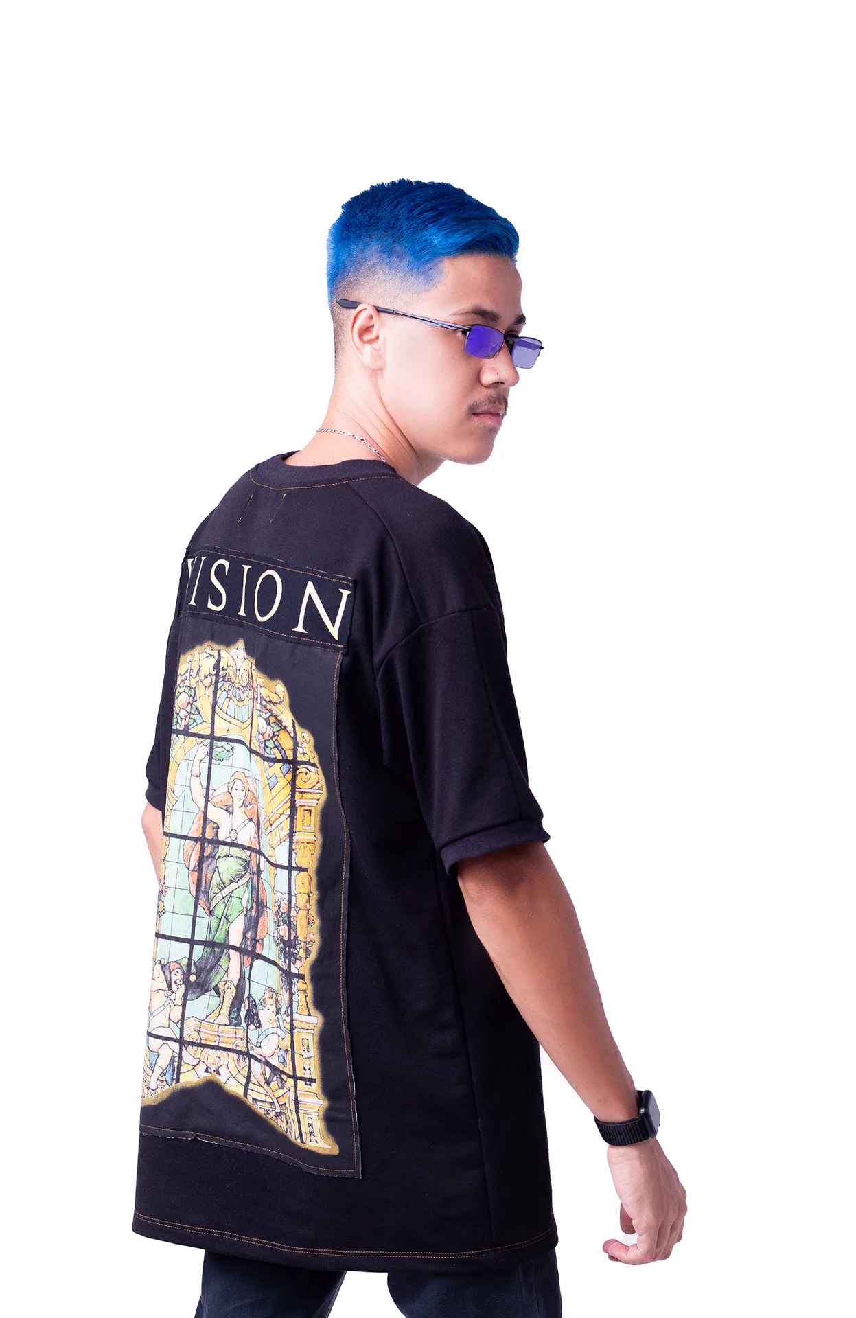 Patrick Richard de cabelo azul e óculos roxos, olhando por cima do ombro, camiseta preta com estampa de vitral